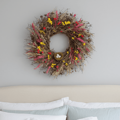 decorative spring wreath, pink and yellow botanicals with birds nest above bed