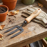 H Potter Dewit Gardening tool with wooden handle on a wooden surface with gloves and pots.