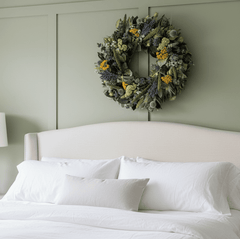 decorative spring wreath with bright botanicals above a bed