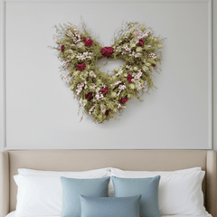 heart shaped valentines wreath with pink and red flowers above a bed