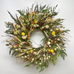 Autumn bramble wreath on wall—handmade H Potter dried botanicals: twigs, cedar, wheat, safflower, strawflower, pine cones.