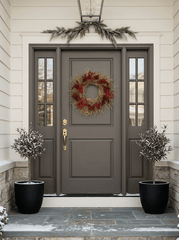 H Potter crimson gold wreath at front entryway with a dark gray double door and matching side panels, decorated with a red berry wreath on the center door, a green garland above, and two potted snow-dusted plants on either side.
