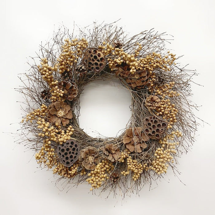 A rustic dried botanical wreath featuring natural twig branches, small beige berries, brown pinecones, and dried lotus pods, displayed against a clean white background.