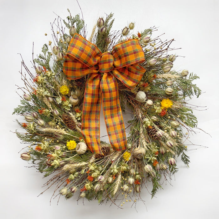 Autumn bramble wreath on wall with bow handmade H Potter dried botanicals: twigs, cedar, safflower, strawflower, pine cones.