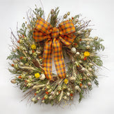 Autumn bramble wreath on wall with bow handmade H Potter dried botanicals: twigs, cedar, safflower, strawflower, pine cones.