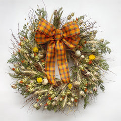 Autumn bramble wreath on wall with bow handmade H Potter dried botanicals: twigs, cedar, safflower, strawflower, pine cones.