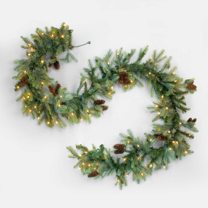 Decorative Christmas wreath with lights and pinecones on a white background