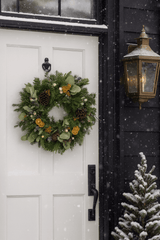 decorative christmas wreath with pinecones and orange slices on a front door