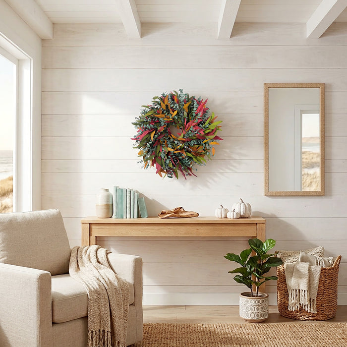 h potter brand colorful autumn wreath made of pinecones, leaves, and ribbons hangs on a white shiplap wall above a light wood console table in a bright, modern coastal-style living room.