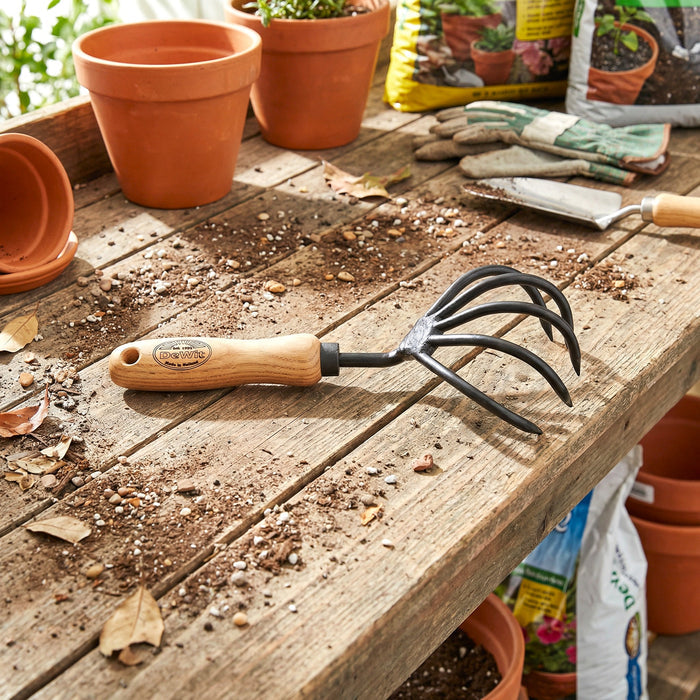 H Potter × DeWit forged 5-tine cultivator with European ash handle, short-handle garden tool for soil aeration and weeding on a garden bench